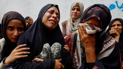 Reuters File photo showing the mother of Palestinian teenager Khaled al-Shinbari holds his shoes during his funeral at al-Shifa hospital, in Gaza City, northern Gaza (28 August 2025)